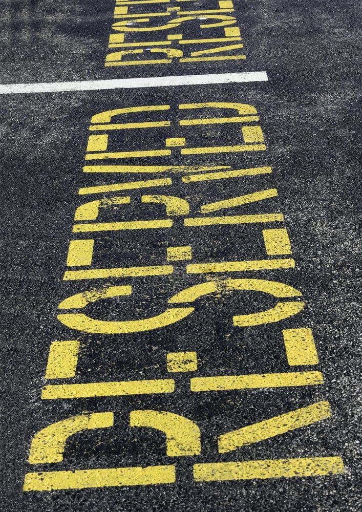 Reserved parking space marked with yellow capital letters painted on black asphalt, for concepts of control, restriction, benefits